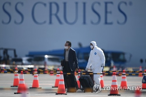 (요코하마 AFP=연합뉴스) 신종 코로나바이러스 감염증(코로나19) 환자가 집단 발생해 일본 요코하마항에 발이 묶인 크루즈선 '다이아몬드 프린세스'호(뒤쪽)에서 한 승선객(왼쪽)이 19일 배에서 내려 이동하고 있다.