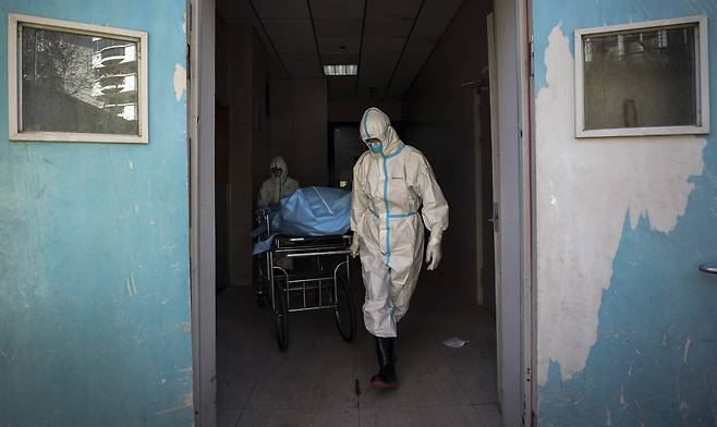 우한의 한 병원에서 2월16일 의료진이 코로나19로 희생된 주검을 옮기고 있다.