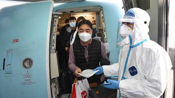 지난 25일 칭다오 공항에 도착한 승객들에 대해 방역 요원이 체온 측정을 하고 있다. 한국에서 온 사람은 14일 강제 격리에 들어간다. [중국 신화망 캡처]