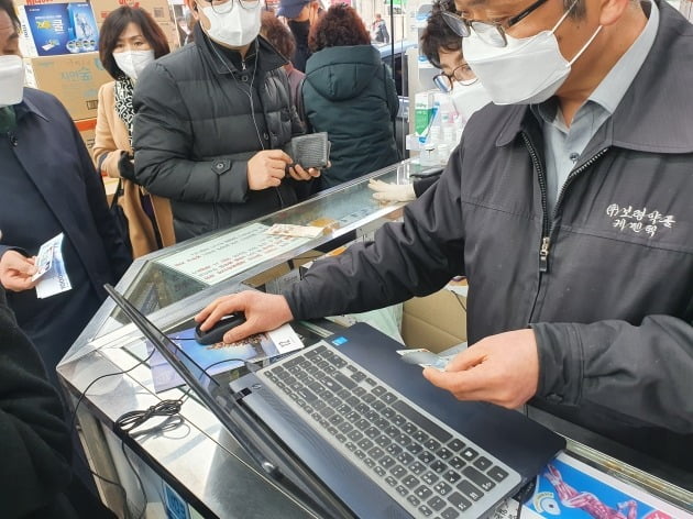 공적 마스크 '1인2매' 구매 제한 첫날인 6일 서울 종로 보령약국에서 직원이 구매자의 신분증을 확인하고 있다.