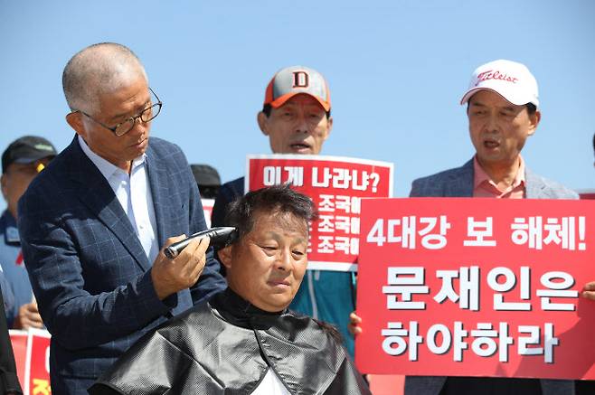 김문수 전 경기지사(왼쪽)가 지난해 9월 서울 종로구 청와대 분수대 광장에서 차명진 전 의원(가운데)의 머리카락을 잘라주고 있다.(사진 = 뉴시스)