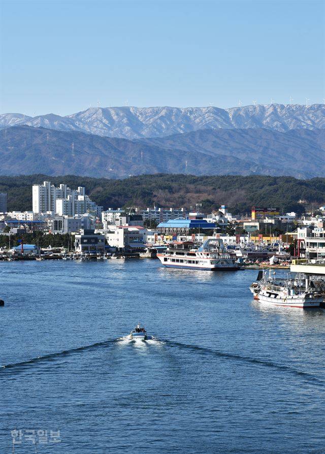 주문진 성황당 뒤편 ‘등대꼬댕이공원’에서 내려다보는 주문진항 풍경. 배가 드나드는 항구를 눈 덮인 선자령이 그림처럼 감싸고 있다.