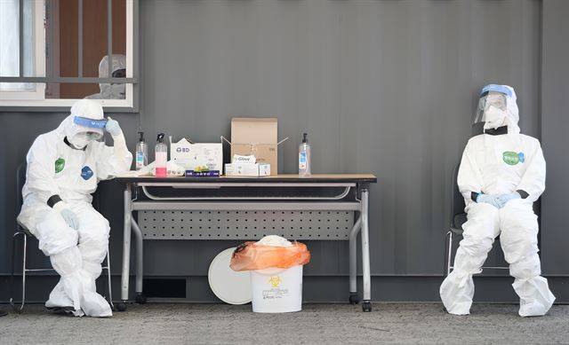 23일 오후 송파구 잠실야구장에 설치된 드라이브 스루 선별진료소에서 방호복을 착용한 의료진이 의자에 앉아 잠시 쉬고 있다. 연합뉴스