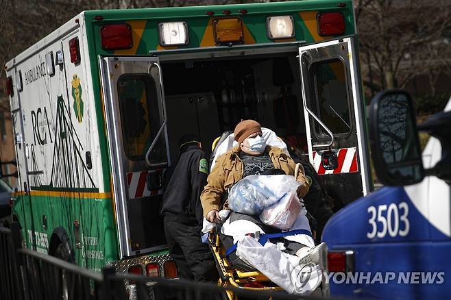 18일(현지시간) 뉴욕 브루클린의 한 병원에서 마스크를 착용한 환자가 응급차량으로 이송되고 있다. [AP=연합뉴스]