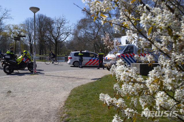 [암스테르담=AP/뉴시스] 네덜란드 경찰이 화창한 주일인 5일 꽃핀 공원에서 상춘객 저지를 위한 순찰을 하고 있다 2020. 4. 5.