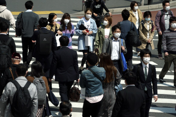 일본 도쿄의 직장인들이 9일 마스크를 모두 쓴 채 횡단보도를 건너고 있다. 아베 신조 총리는 지난 7일 도쿄를 비롯한 7개 현에 코로나19 긴급사태를 선언했다.도쿄 AP 연합뉴스