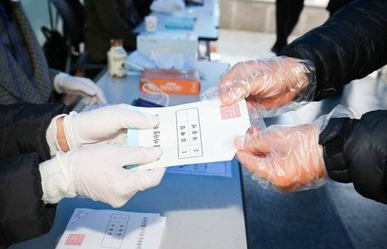광주광역시 수완동 우산신협 투표소를 찾은 신협 조합원이 비닐장갑을 끼고 투표용지를 받고 있다. 프리랜서 장정필
