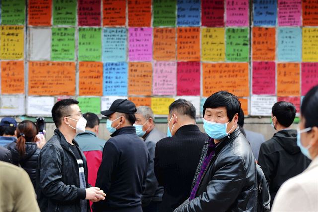 중국 산둥성 동부 칭다오의 인력시장에서 4일 마스크를 쓴 노동자들이 일자리를 찾기 위해 벽에 붙은 구인 공고를 보고 있다. 칭다오=AP 연합뉴스