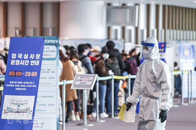 방호복과 각종 보호 장구로 무장한 검역 관계자가 17일 오후 인천국제공항 제2여객터미널 2층 입국심사장에서 대기 중인 입국자들 옆을 지나고 있다. 이 관계자의 손에 들린 서류는 모든 입국자들이 의무적으로 작성해야 하는 특별검역신고서다. 영종도=이한호 기자