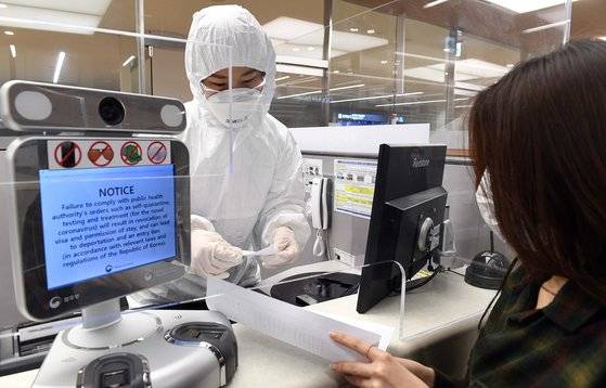 전신 방호복을 입은 인천국제공항 출입국 외국인청 입국심사관이 지난 8일 오후 유증상자 전용 입국심사대에서 입국심사 후 자가격리 지침을 설명하고 있다. 연합뉴스