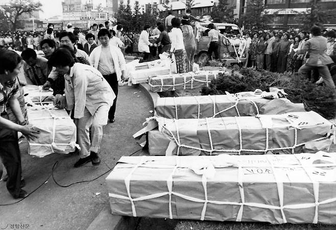 1980년 5월 당시 광주 금남로를 가득 메운 시민군과 차량(왼쪽 사진), 도청 앞 광장에서 희생자들의 관을 옮기고 있는 유가족들.   민주화운동기념회 제공