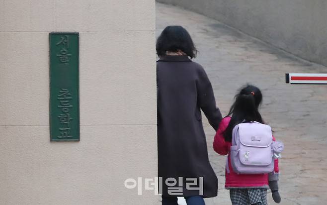 코로나19로 개학연기 여부 발표가 예정된 지난 3월 서울 종로구 한 초등학교에서 어린이가 학부모와 함께 돌봄교실을 위해 등교하고 있다.(사진=뉴시스)