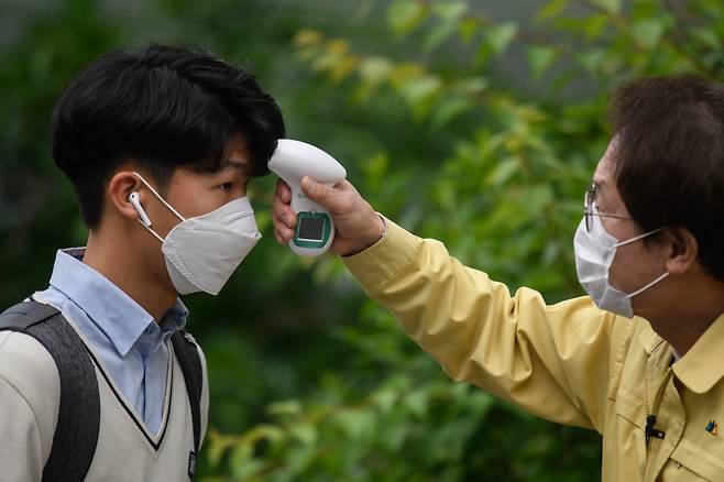 19일(현지시간) 서울의 한 고등학교에서 등교 중인 학생의 체온을 체크하고 있다/사진=AFP