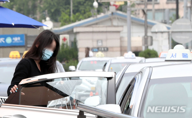 [서울=뉴시스] 박미소 기자 = 정부가 오는 26일부터 승객이 버스나 택시를 탈 때 운송사업자와 운수종사자가 마스크를 착용하지 않을 경우 관할 시·도지사가 개선 조치를 내리도록 한 25일 오후 서울 용산구 서울역 인근 택시 정류장에서 시민들이 마스크를 쓰고 택시에 탑승하고 있다. 2020.05.25.  misocamera@newsis.com