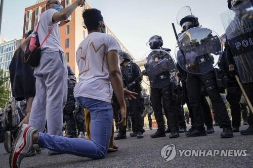 1일(현지시간) 미 워싱턴DC에서 흑인 사망에 항의하는 시위에 나선 참가자가 경찰관들 앞에서 무릎을 꿇는 동작을 하고 있다. [AFP=연합뉴스]