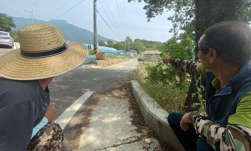 평산마을 주민 (양산=연합뉴스) 김동민 기자 = 문재인 대통령 내외가 경남 양산 하북면 평산마을 한 주택을 매입했다는 소식이 전해진 5일 마을 입구에서 주민들이 문 대통령 사저 방향을 손으로 가리키며 대화하고 있다. 2020.6.5