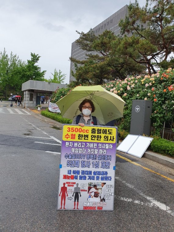 고 권대희씨 어머니 이나금씨가 서울 서초동 검찰청 앞에서 1인 시위를 하고 있는 모습. 이씨가 든 피켓에 '3500cc 출혈에도 수혈 한 번 안 한 의사'라는 문구가 선명하다. 고 권대희씨 유족 제공.