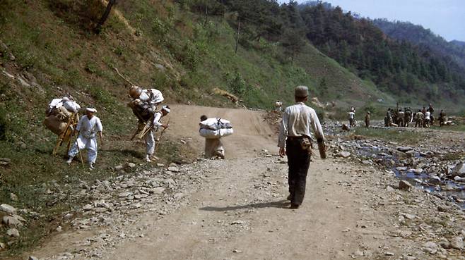 1951년 3월 초 어느 산간마을에서 공사하는 군인들 사이로 지나가는 피란민 행렬