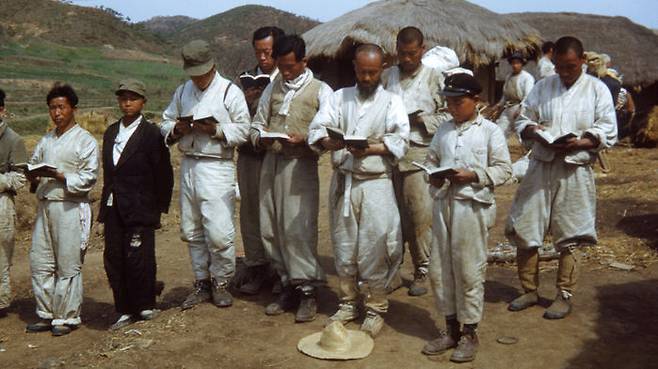 1951년 피란길 도중 마을 집 앞에서 성경책 읽는 사람들