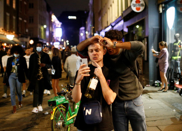 4일(현지 시각) 영국 런던 소호 거리에서 남성 2명이 사진 포즈를 취하며 스마트폰을 들여다보고 있다. /로이터 연합뉴스
