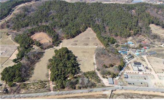 공중에서 본 부여 능산리 고분군 전경. 중간에 일곱개의 무덤 자리가 보이는 곳이 능산리 중앙고분군이며, 왼쪽 상단에 숲으로 둘러싸인 네모진 구역이 지난 2016년 4기의 무덤이 발굴된 서고분군이다.