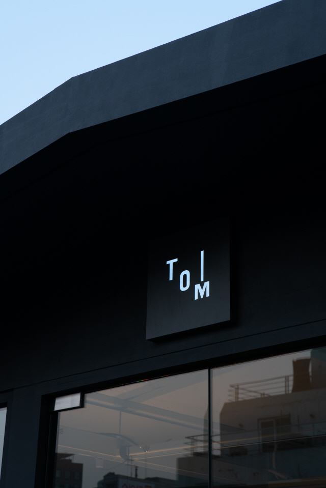 T.O.M.Kitchen(티오엠키친)의 로고. M자에 선을 붙여 포크를 연상시킨다. 취향 맞춤 모듈 주방가구로 식문화 발전에 기여하고 싶은 바람을 담았다.