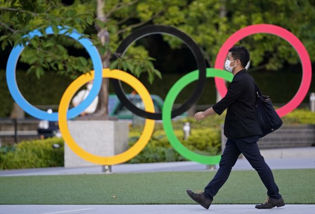 한 시민이 도쿄 올림픽경기장 근처에 설치된 오륜기 모양의 조형물 옆을 지나고 있다. EPA 연합뉴스