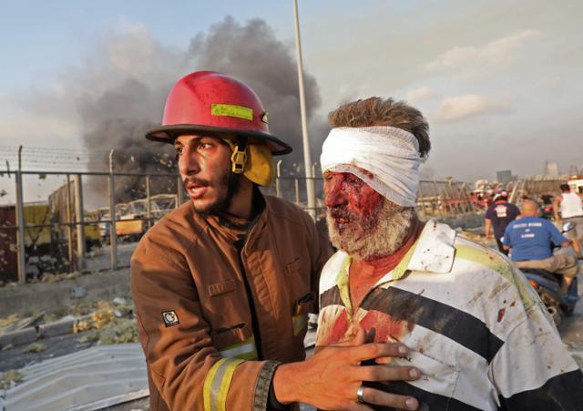 소방대원이 4일 레바논 베이루트 폭발 현장에서 부상자를 부축하고 있다. 베이루트=AFP 연합뉴스
