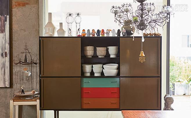 옻칠한 허명욱 작가의 그릇장. 그릇과 꽃병, 토기, 디자이너의 캐릭터들이 살아 있는 작은 소품까지 어느 하나 스토리가 없는 게 없다. 옆에 놓여 있는 샹들리에는 2002년부터 쓰던 소품.