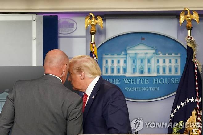 (워싱턴 로이터=연합뉴스) 도널드 트럼프 미국 대통령이 10일(현지시간) 워싱턴DC 백악관에서 열린 신종 코로나바이러스 감염증(코로나19) 언론 브리핑장을 떠나기에 앞서 비밀경호국 요원과 귀엣말을 나누고 있다. sungok@yna.co.kr