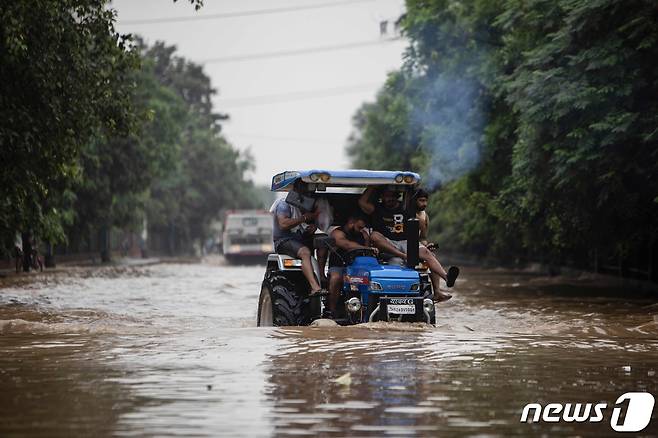 19일 인도 수도 뉴델리 외곽 구르가온에서 폭우로 도로가 잠겨 통근자들이 트랙터를 타고 출근하고 있다. © AFP=뉴스1