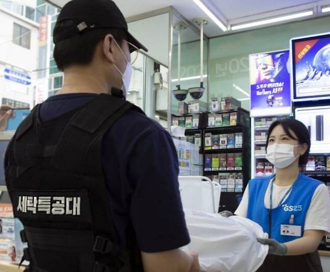 GS25 직원이 세탁특공대 직원에게 고객의 세탁물을 전달하고 있다/사진제공=GS리테일