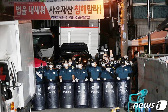 21일 오후 서울 성북구 사랑제일교회 압수수색에 나선 경찰이 방역복 차림으로 좁은 진입로를 통해 교회로 향하고 있다. 경찰은 교인 명단을 비롯해 광복절 집회 참석자 명단 등을 집중적으로 확보할 예정이다. 2020.8.21/뉴스1 © News1 민경석 기자