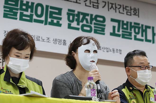 ⓒ연합뉴스8월6일 서울 영등포구 전국보건의료산업노동조합에서 열린 ‘보건의료 현장 불법의료 실태고발긴급 기자간담회’에서 가면을 착용한 상급 종합병원 간호사가 증언하고 있다.