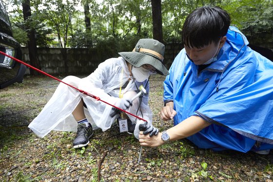 홍섬 학생기자와 용석현(오른쪽) 매니저가 어닝 텐트에 연결된 줄을 고정하기 위해 땅에 펙(말뚝)을 박고 있다.