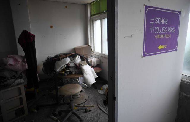 지난달 25일 전북 군산 서해대 학보사 사무실에 옷가지와 이불, 상자가 먼지를 뒤집어 쓴 채 어질러져 있다. 이 대학 학보는 학생 수가 줄면서 폐간됐다. ‘서해대학 학보사’ 플래카드만 문에 붙어 있다. 군산=윤성호 기자