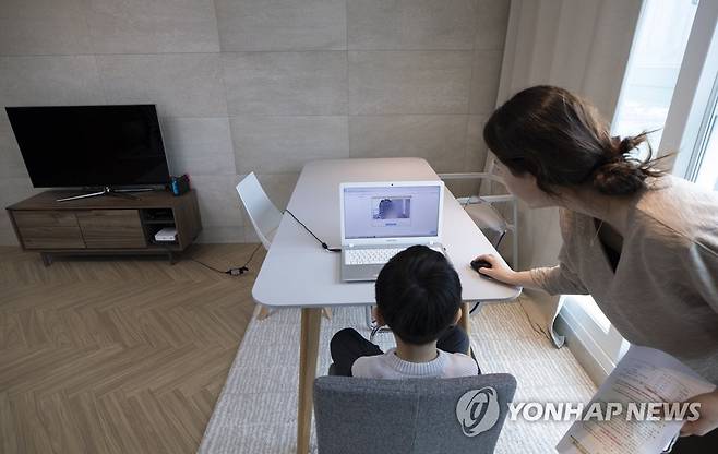 엄마와 집에서, 초등학교 '온라인 입학식' 서울의 한 가정에서 초등학교에 입학한 신입생 어린이가 엄마와 함께 노트북 화면을 통해 온라인 입학식을 갖고 있다. [연합뉴스 자료사진]