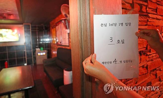 입장 인원 제한하고 (대전=연합뉴스) 김준범 기자 = 14일 오후 대전시 대덕구 송촌동 한 노래방에서 업주가 입장 인원을 제한하는 내용의 안내문을 붙이고 있다. 신종 코로나바이러스 감염증(코로나19) 확산에 따른 집합금지 조치로 문을 닫았던 대전지역 노래방과 유흥주점 등은 이날 영업을 재개한다. 2020.9.14 psykims@yna.co.kr