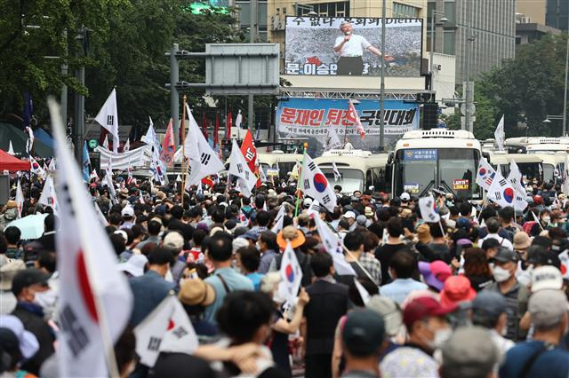 - 지난 15일 서울 종로구 동화면세점 앞에서 열린 광화문 집회에서 참석자들이 대형 스크린을 통해 전광훈 목사의 발언을 듣고 있다. 이날 집회와 관련한 코로나19 확진자가 300명을 넘어서면서 집회를 허가한 재판부에 대한 비판이 제기되고 있다. 연합뉴스