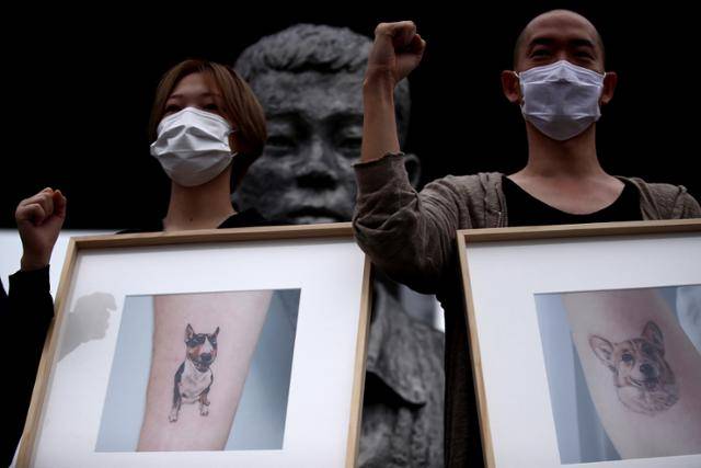 김도윤(오른쪽) 민주노총 타투유니온 지회장과 조합원들이 지난 7월 서울 종로5가 전태일다리에서 열린 제12차 전태일 50주기 캠페인 기자회견에서 타투노동자 일반직업화를 호소하며 반려동물 타투 사진 액자를 들고 있다. 연합뉴스