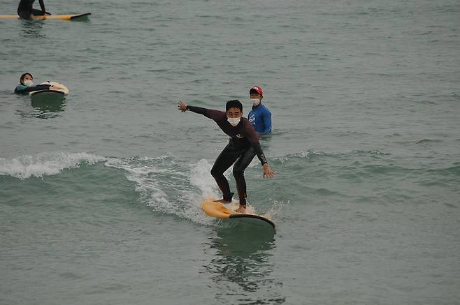 부산 송정해수욕장에서 마스크를 쓰고 서핑을 즐기는 서퍼의 모습. 서프홀릭 제공