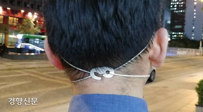 마스크 끈으로 인한 귀 기형을 방지하고 귀에 부담을 줄이려면 고리를 이용해 끈을 머리 뒤로 묶어주는 것이 좋다. 경향신문 자료사진