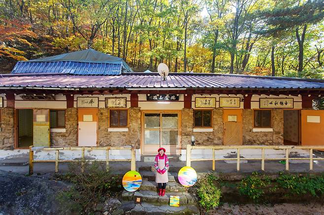 속리산 ‘비로산장’을 운영하는 김은숙씨가 산장 본채 앞에 섰다. 양옆에 놓인 그림은 화가인 김씨가 속리산에서 영감을 받아 그렸다. 건물 안팎에 걸린 붓글씨는 대부분 서예와 서각에 능했던 아버지 고 김태환씨, 그와 교유한 이들이 남긴 작품이다. /이신영 영상미디어 기자
