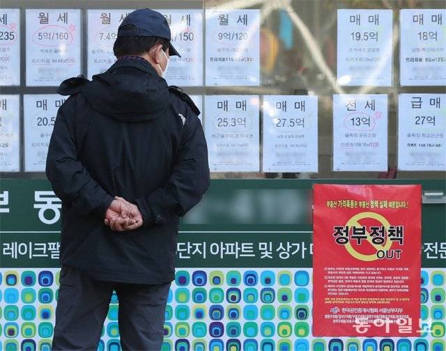 전세난이 가중되고 있는 가운데 11일 서울 송파구의 한 부동산중개업소 앞에서 한 시민이 창문에 붙은 ‘정부 정책 OUT(아웃)’ 포스터를 들여다보고 있다. 한국공인중개사협회 서울남부지부 명의의 이 포스터에는 ‘부동산 가격폭등은 부동산 정책 실패 때문입니다’라고 적혀 있다. 홍진환 기자 jean@donga.com