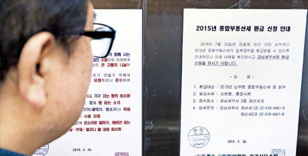 서울의 한 아파트 입주민이 30일 엘리베이터에 붙어 있는 종합부동산세 환급 신청 안내문을 살펴보고 있다. /강은구 기자 egkang@hankyung.com