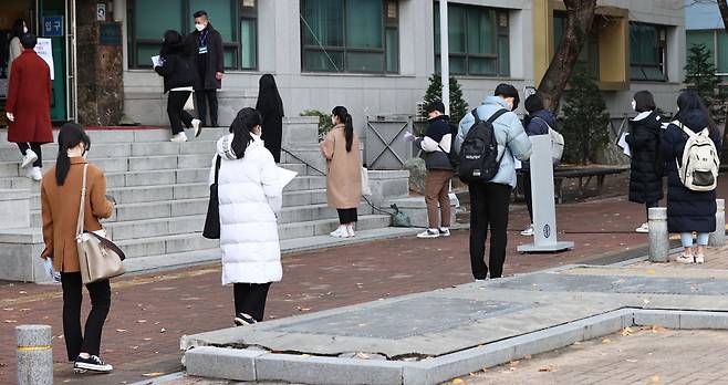 Early action applicants wait outside a Seoul university building for admissions interview Sunday. (Yonhap)