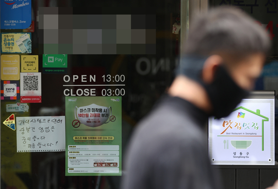 A man wearing a face mask walks past a restaurant with a temporary closure notice in Seoul. [YONHAP]