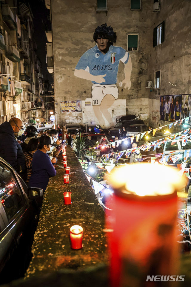 [나폴리=AP/뉴시스]25일(현지시간) 이탈리아 나폴리에 있는 축구 전설 디에고 마라도나의 벽화 아래 사람들이 모여 촛불을 밝히며 그의 죽음을 애도하고 있다. 1986년 아르헨티나를 월드컵 우승으로 이끈 아르헨티나 축구 영웅 디에고 마라도나가 25일 아르헨티나 부에노스아이레스 자택에서 심장마비로 타계했다. 향년 60세. 2020.11.26.