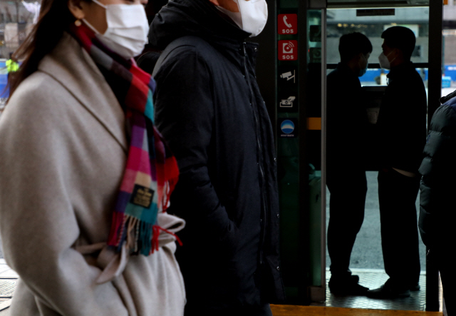 지난 23일 서울 시내 공중전화 부스에서 시민들이 추위를 피하고 있다./연합뉴스