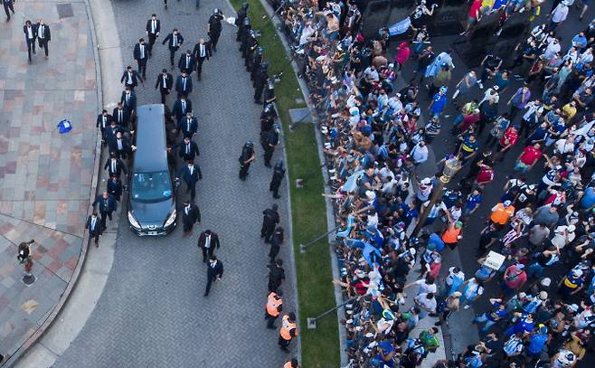 26일(현지시간) 마라도나의 관을 실은 영구차가 팬들이 몰린 아르헨티나 부에노스아이레스의 대통령궁 카사 로사다를 떠나고 있다. 마라도나는 그의 부모가 안장된 베야비스타 공원묘지에 묻힌다.(사진=AP/뉴시스)